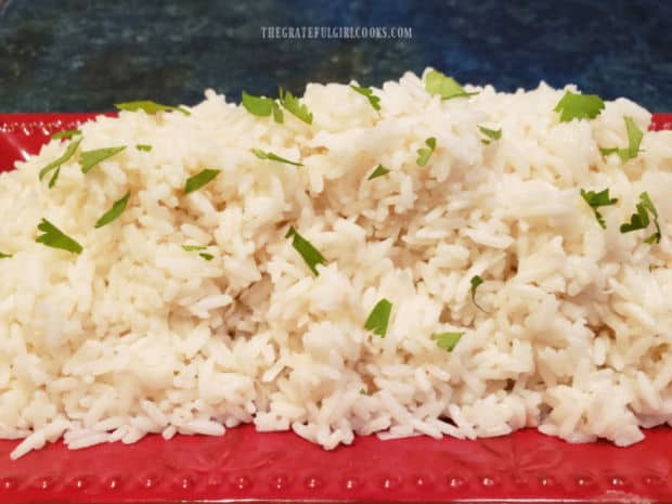 Creamy coconut rice is served, garnished with chopped fresh parsley.