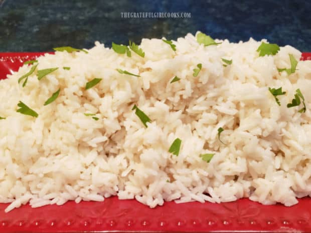 Creamy coconut rice is served, garnished with chopped fresh parsley.