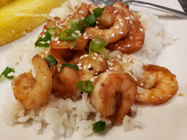 Honey garlic shrimp on rice, drizzled with lime juice, and sprinkled with sesame seeds and green onions.
