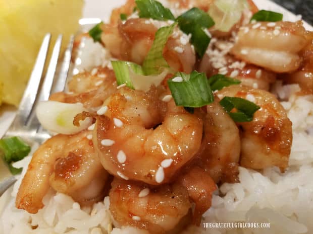 Sesame seeds and green onions top a serving of honey garlic shrimp on rice.