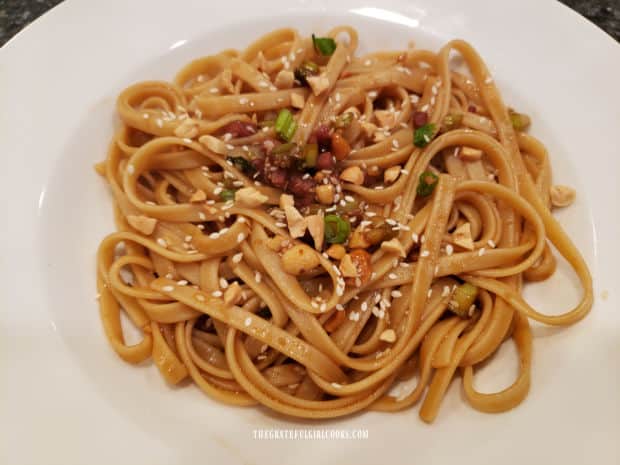 A white bowl, full of simple Szechuan noodles, which are ready to eat.