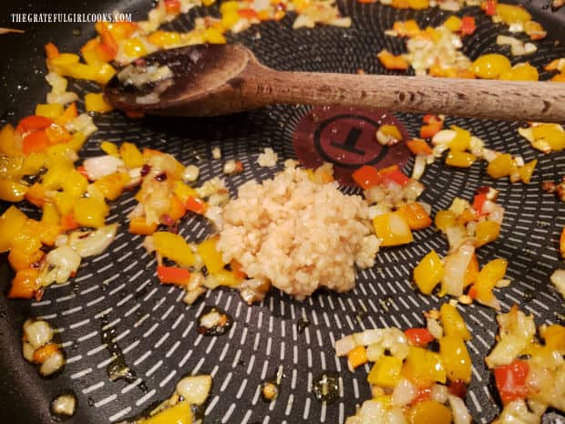 Minced garlic is added to the sauteed veggies in the skillet.