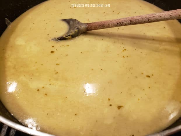 The green curry sauce cooks in a large skillet before pouring over cooked mussels.