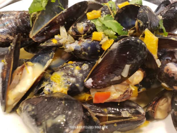 Thai green curry mussels are served in a large white bowl.