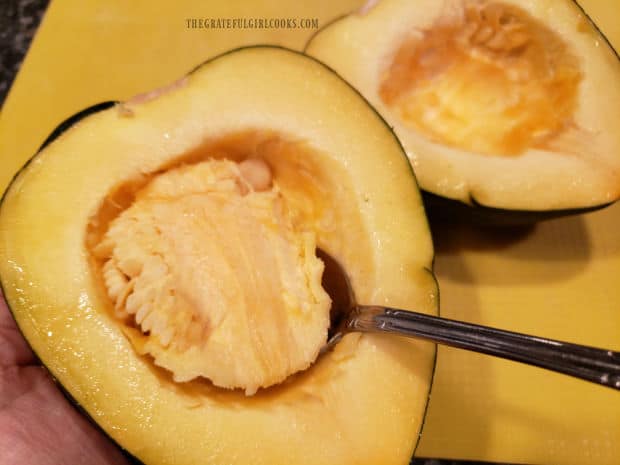 After slicing it in half, the acorn squash seeds and stringy pulp are removed.