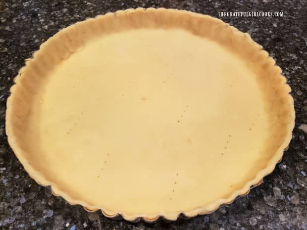 Pie dough is placed and shaped in a tart pan, to be ready for the filling.