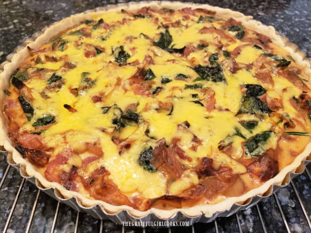A baked bacon, onion and spinach tart cools on wire rack for 5 minutes before serving.