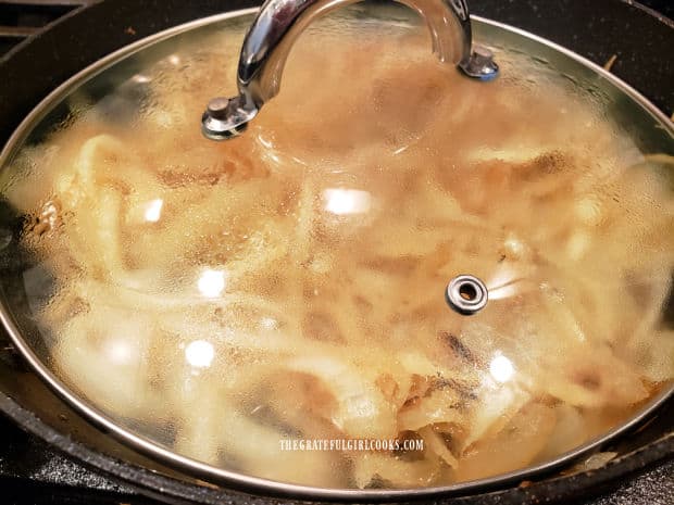 A lid is placed on the skillet of onions while they cook and caramelize.