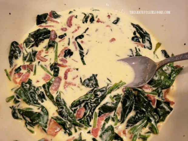 Cooked bacon and spinach are added to the tarts egg filling in a large bowl.