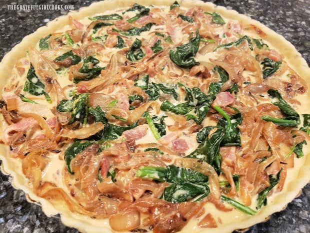 Filling for the bacon, onion and spinach tart is poured into prepared crust in a tart pan.