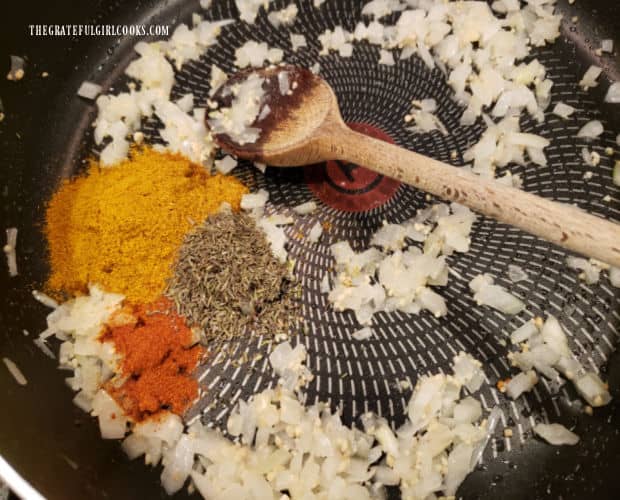 Curry powder, thyme and paprika are added to cooked onion/garlic mixture in skillet.