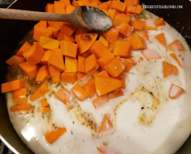 Cubes of butternut squash, canned coconut milk and vegetable broth are added to the skillet.