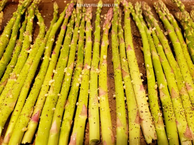 The asparagus stalks are now seasoned with salt and pepper.