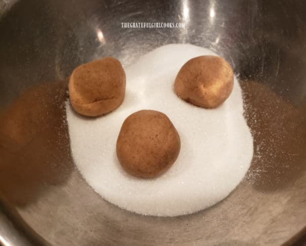 Dough balls are coated in granulated sugar before baking.