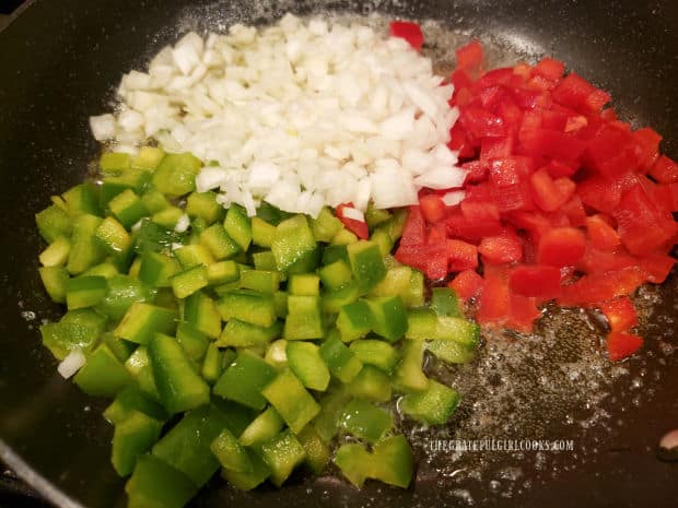 Onions with red and green bell peppers cook in butter and oil in skillet.