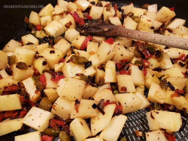 Potato cubes are combined with the charred bell peppers and onions in skillet.