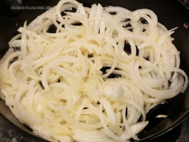 Thinly sliced onions are cooked in melted butter in skillet.