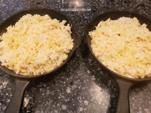 Two 4" cast iron skillets filled with cheese dip before baking.