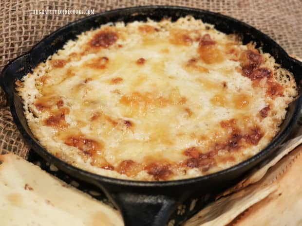 A skillet of Guinness Baked Cheese Dip is served with crackers as an appetizer.