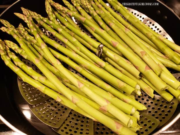 Asparagus stalks are steamed in basket over water in skillet until crisp tender.