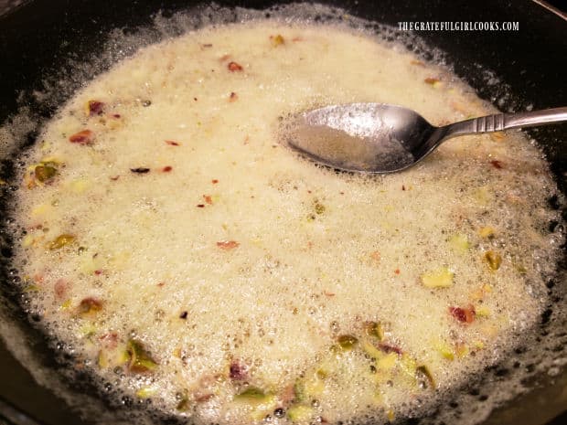 Orange juice and orange zest are added to butter and pecans in skillet, creating a foamy liquid.