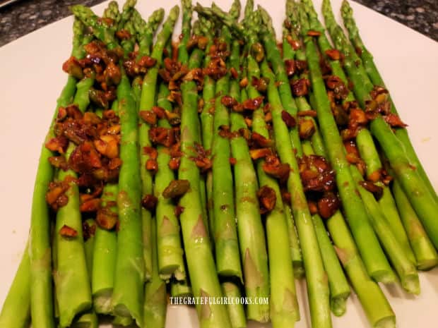 Pistachio Asparagus in Orange Sauce is served hot, on a white platter.