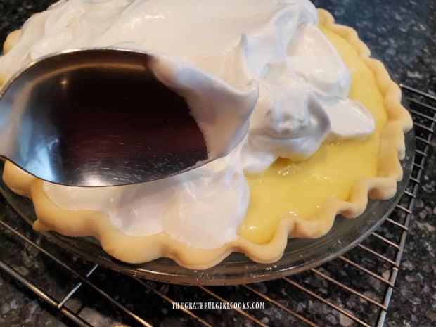 Meringue is carefully spread over the surface of warm pie filling, all the way to seal the edges.