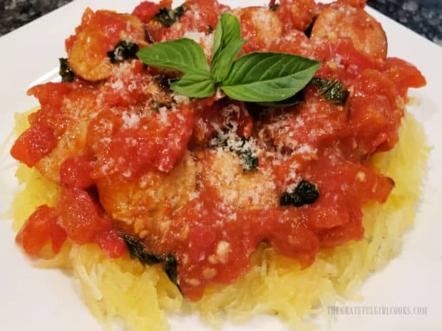 Spaghetti Squash Italiano is served with grated Parmesan and fresh basil sprig on top.