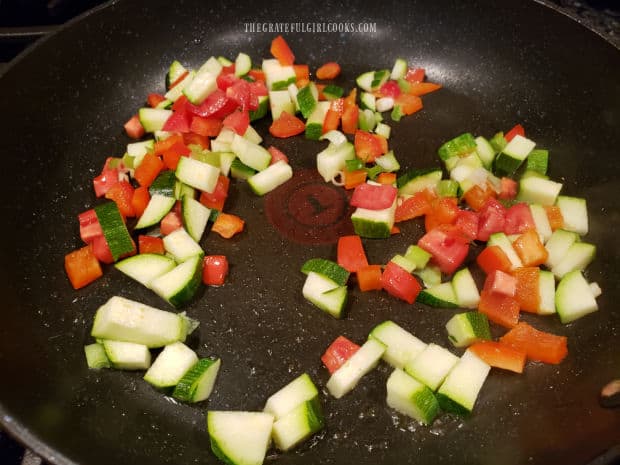 Scallions, bell peppers, zucchini and tomatoes are cooked until tender in large skillet.