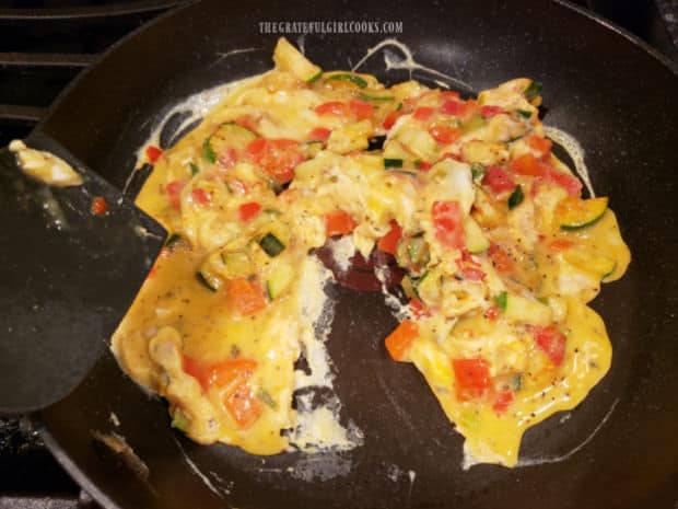 Using a spatula to mix and cook the TexMex veggie egg scramble.