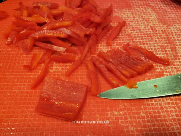 Red bell pepper is sliced into thin matchstick shapes for the coleslaw.