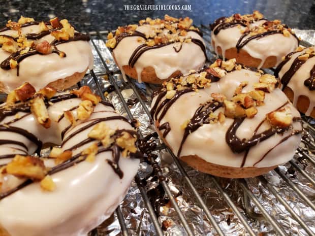 Chopped toasted nuts and melted chocolate are added to the top of each doughnut.