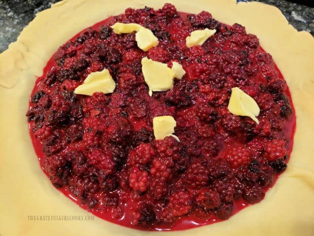 Blackberry pie filling is added to crust and dotted with butter before adding top pastry crust.