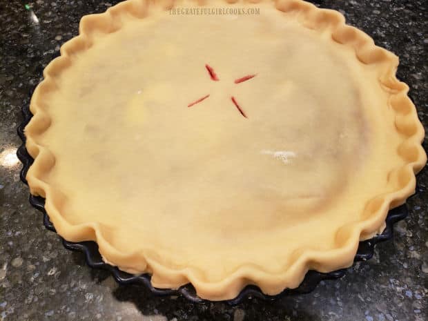 Top crust is added and shaped, then steam vents are cut into the top before baking.