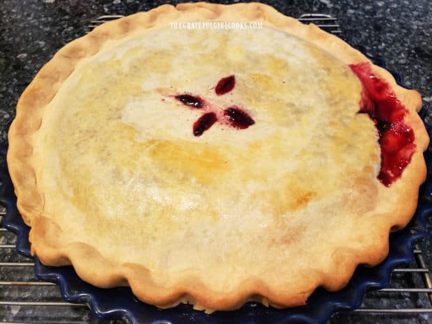 The finished blackberry pie is golden brown on top and the filling is bubbly around the edges.