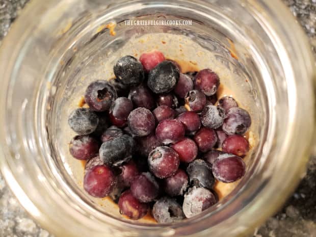 Part of the blueberries are added to the jar, then gently stirred into the oat mixture.