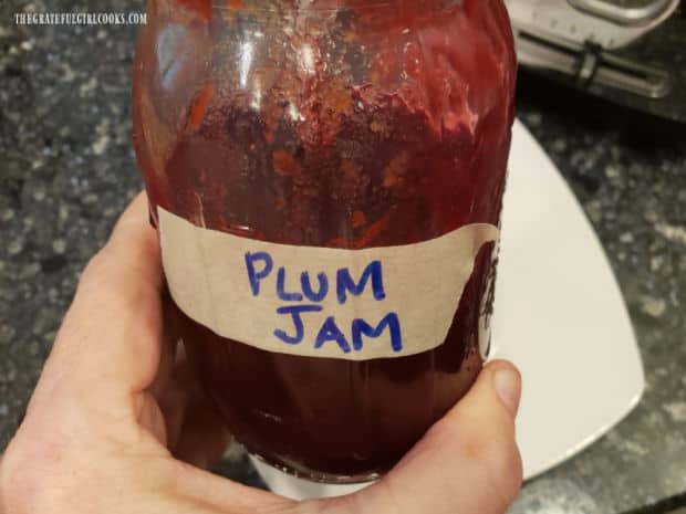 A pint jar of Italian Plum Jam, only half full after a lot of jam has been gobbled up.