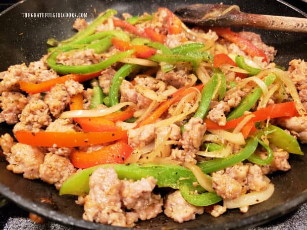 Cooked Italian sausage is added back into skillet with cooked peppers and onions.