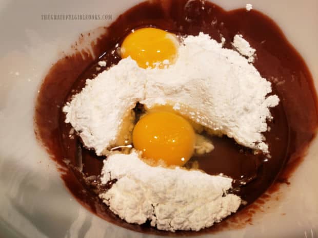 An egg, an egg yolk, and powdered sugar are whisked in bowl until combined.