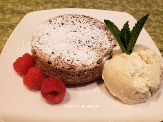 Dusted with powdered sugar, air fryer chocolate lava cake is served with ice cream and raspberries.