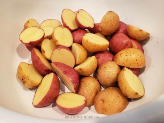 Red and gold mini potatoes are rinsed clean, then dried and cut in half before seasoning.