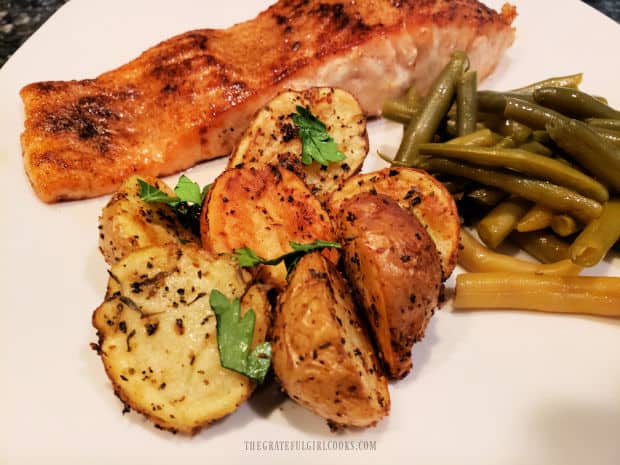 Salmon and green beans served on a plate with air fryer crispy mini potatoes.