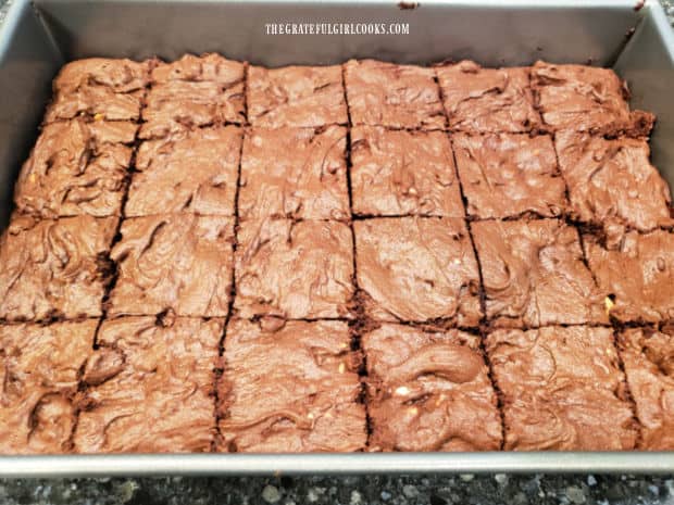 After baking, the chocolate peanut butter brownies are cut while still hot into 24 portions.