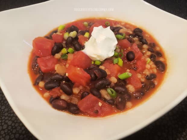 The easy black bean stew is garnished with chopped green onions and sour cream to serve.