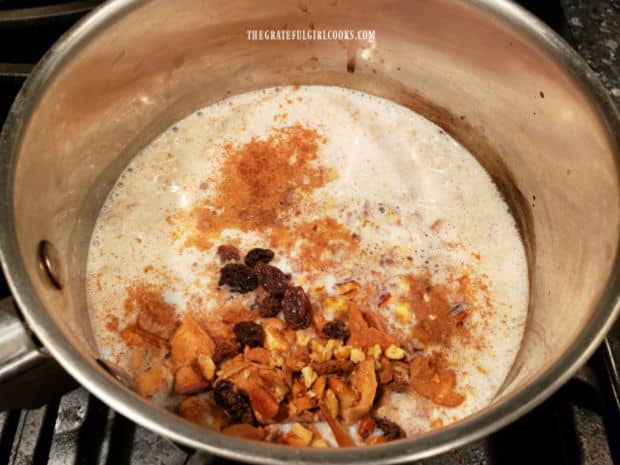 Oats, raisins, apple, pecans, brown sugar, cinnamon and salt are added to the milk in the pan.