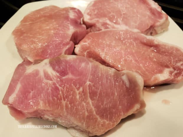 Four boneless pork chops are patted dry, then are ready to be marinated.