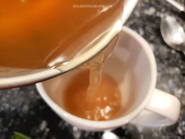 Hot lemon mint tea is poured into a mug once done.