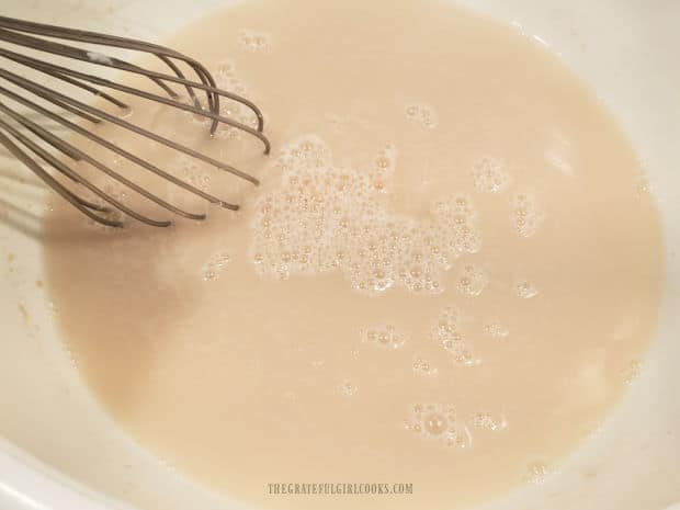 Dry active yeast is whisked into warm water in a large, 2 gallon bowl.