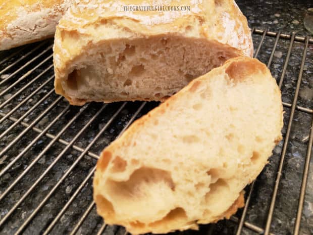 Slices of the no knead mini loaves on a wire rack, ready to be buttered and eaten.