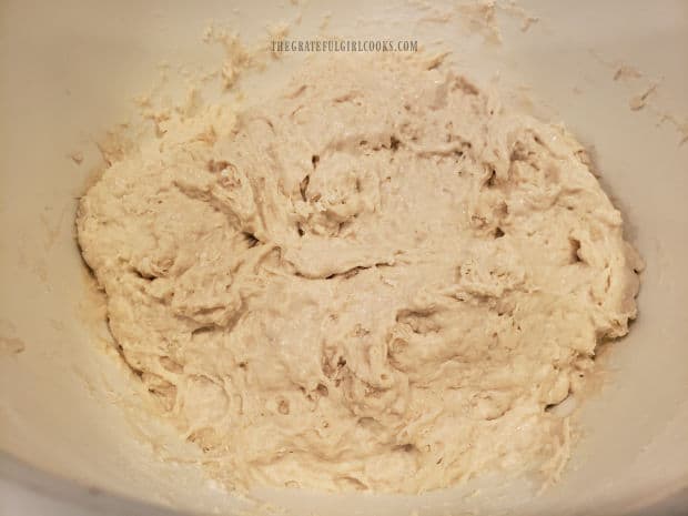 Thick and sticky, the dough is combined in a large bowl for the no knead mini loaves.